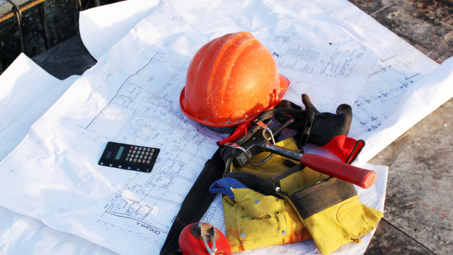 Bauhelm, Werkzeuge und Baupläne als Symbol für hohe Vorleistungen